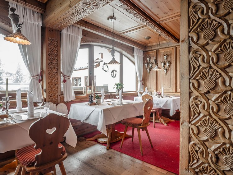 Gemütlicher Holzrestaurantbereich mit geschnitzten Wänden und weiß gedeckten Tischen