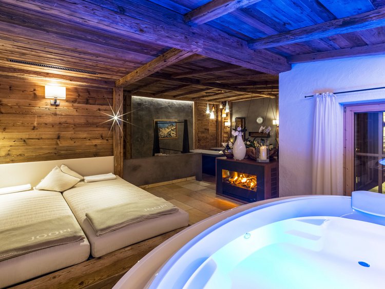 Cozy room with hot tub, fireplace, and double bed in wooden setting