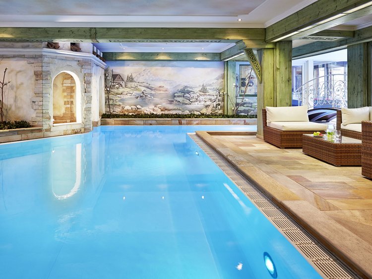 Indoor pool with blue lighting and cozy seating area