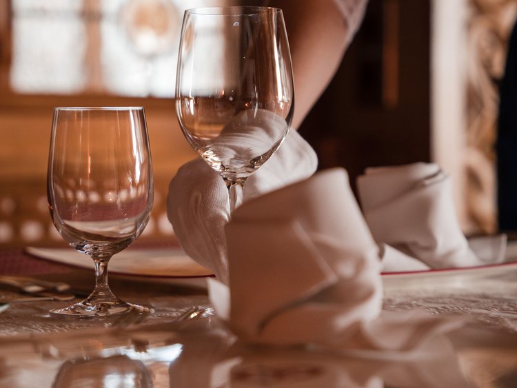 Kellner platziert Weinglas neben Wasserglas auf gedecktem Tisch