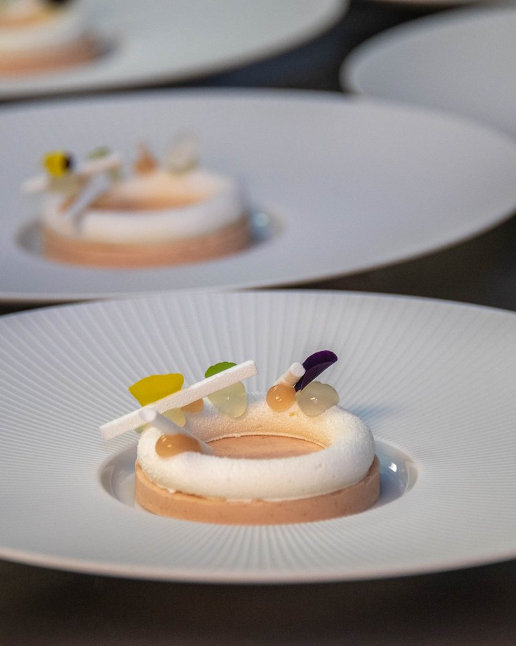 Mehrere kunstvoll dekorierte runde Desserts auf weißen Tellern