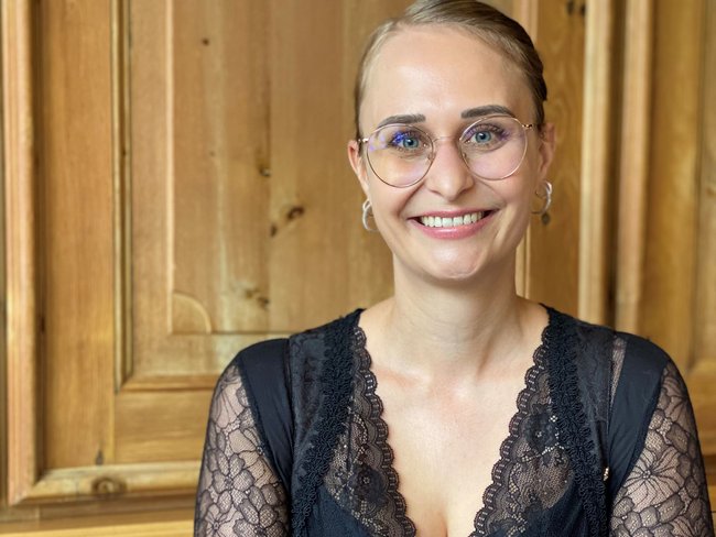 Frau mit Brille und Namensschild vor Bergmotiv im Jagdhof Spa-Hotel