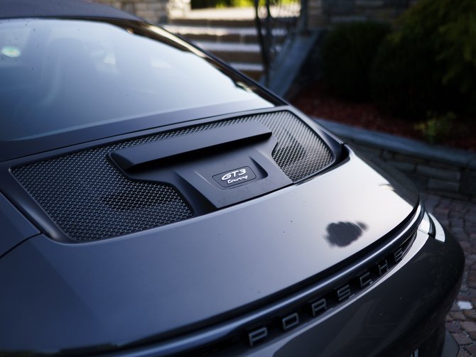 Heck eines dunklen Porsche 911 GT3 RS vor Steintreppen und Häusern