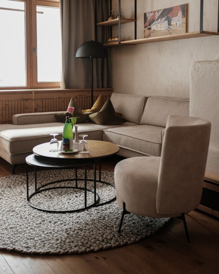 Gemütliches Wohnzimmer mit Sofa, Sessel, zwei Tischen und Fenster