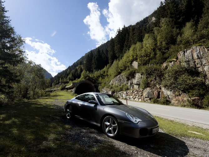 Grauer Sportwagen an einer Bergstraße vor einem Tunnel