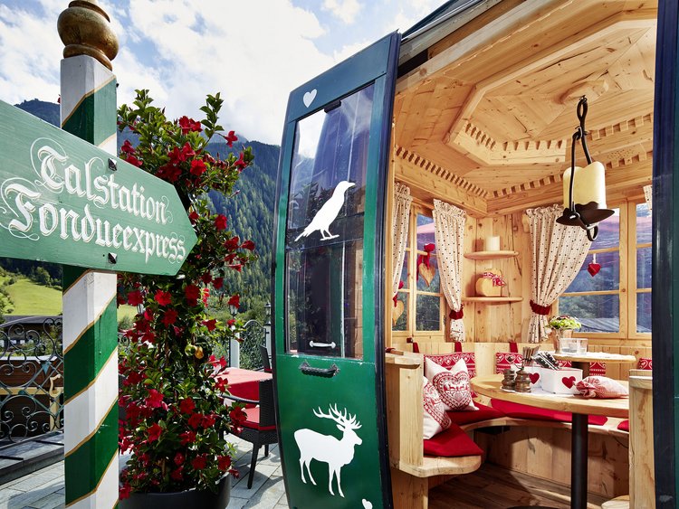 Gemütliche Holzhütte mit Sitzbereich und grünem Türschild im Alpenstil