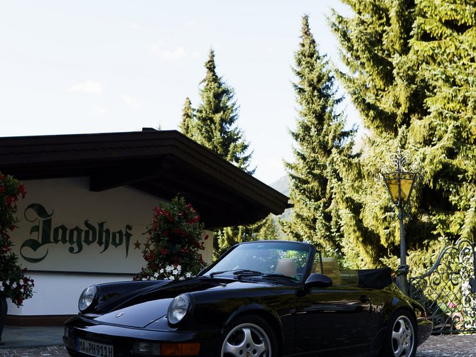 Schwarzes Cabrio vor dem Jagdhof auf einem gepflasterten Hof