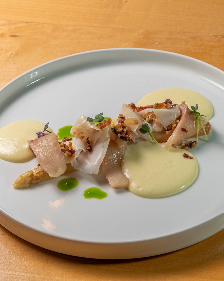 Fein angerichtetes Fischgericht mit Sauce und Kräutern auf weißem Teller