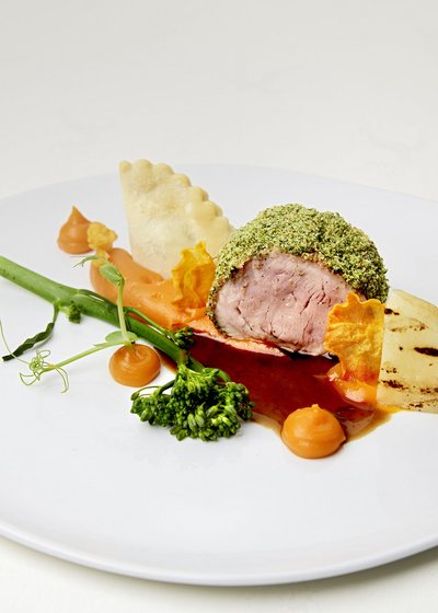 Gourmet dish with herb crust, carrot sauce, broccoli, and grilled vegetables