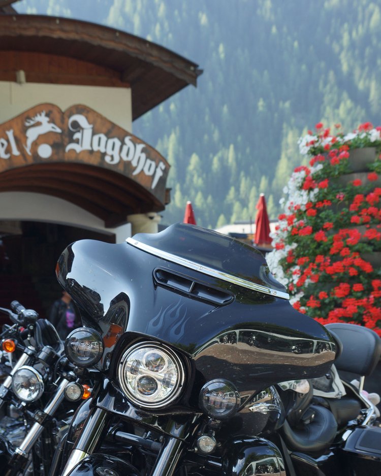 Mehrere Motorräder vor dem Hotel Jagdhof mit Bergen und Blumen im Hintergrund
