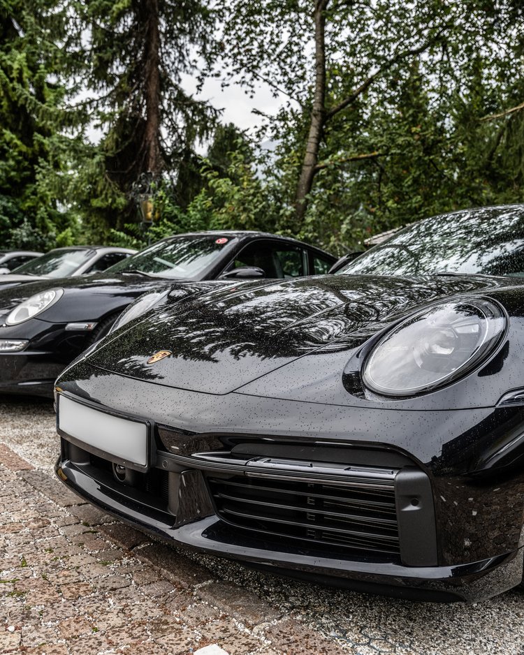 Mehrere geparkte Porsche-Sportwagen neben einem Waldgebiet