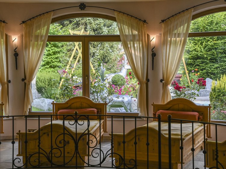 Bright room with wooden beds and view of colorful garden outside