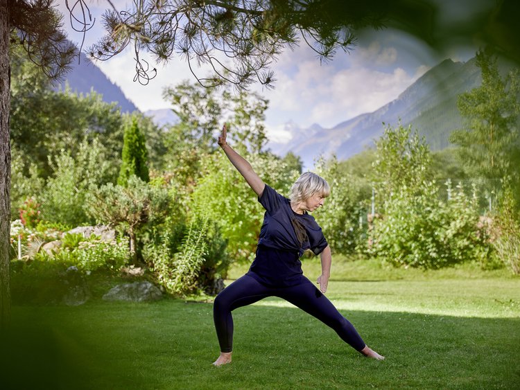 Woman doing yoga in garden with mountain view on a sunny day