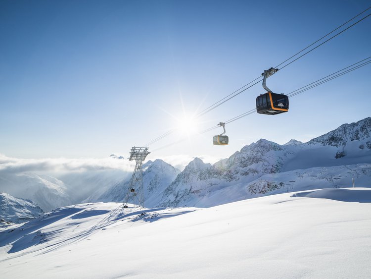 Seilbahn über schneebedeckten Bergen bei sonnigem Himmel