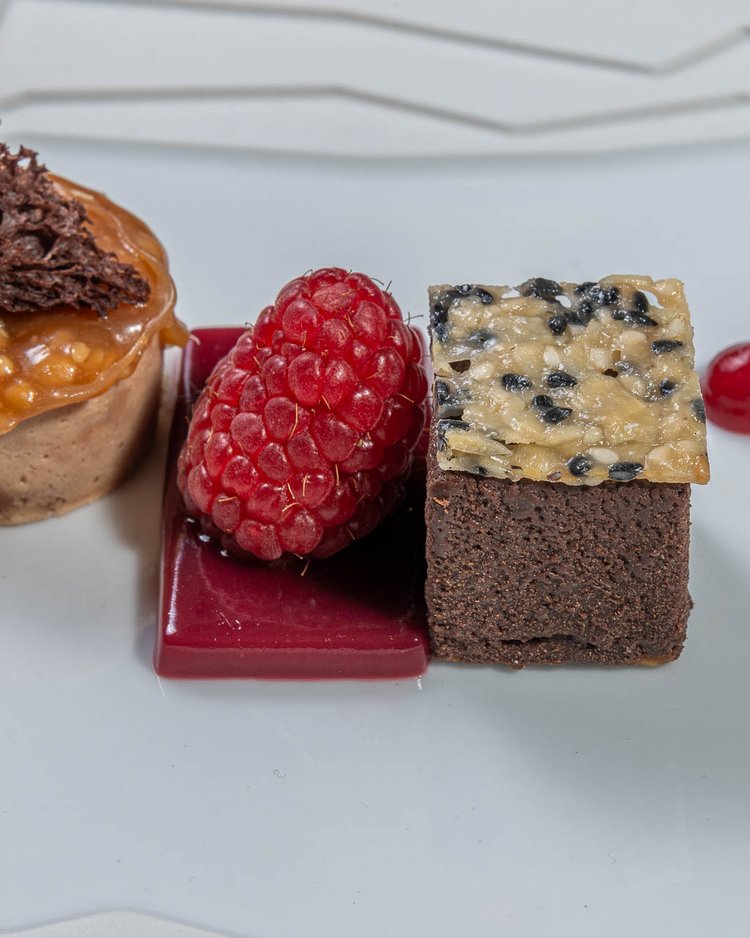 Feines Dessert mit Schokolade, Himbeeren und Fruchtsauce auf weißem Teller