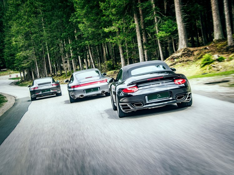 Drei Sportwagen fahren auf einer kurvigen Waldstraße