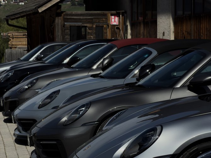 Reihe grauer Sportwagen vor einem Gebäude in einer hügeligen Landschaft