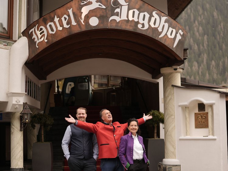 Drei Personen stehen vor dem Eingang des Hotels Jagdhof mit rotem Teppich